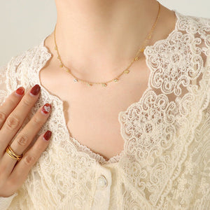 Close-up of a person wearing a gold necklace and gold ring with a white lace garment.