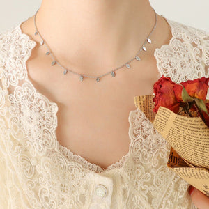 Necklace on a mannequin with a lace garment and red flowers in the background