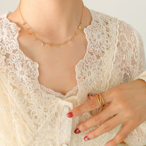 Close-up of a person wearing a gold necklace and ring, with a white lace garment.