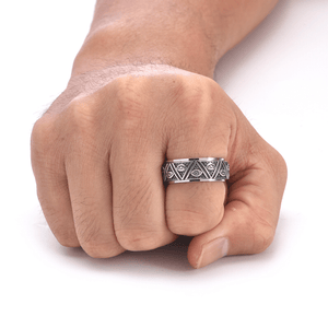 Hand wearing a silver ring with intricate design on a white background