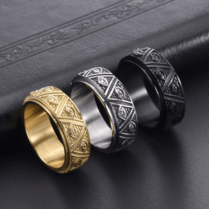 Three ornate rings in gold, silver, and black on a dark textured surface