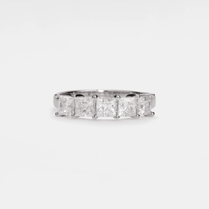 Silver ring with four princess-cut diamonds on a light gray background