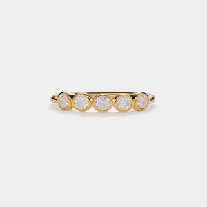Gold ring with five diamonds on a light beige background