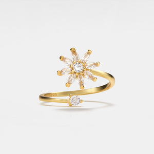 Gold ring with diamond flower design on a light gray background