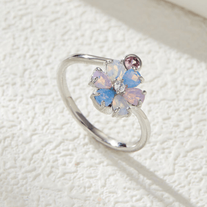 Silver ring with multicolored gemstones on a textured white surface