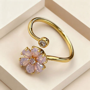Gold earring with pink gemstones on a beige background