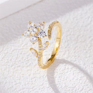 Gold ring with diamond flower design on a white textured background