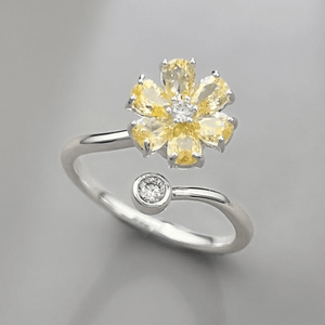 Silver ring with yellow gemstones on a gray background