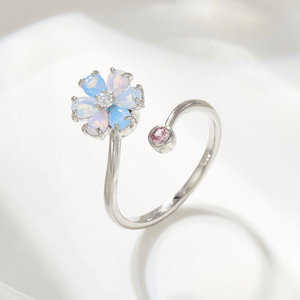 Silver ring with a flower-shaped opal stone and pink gem on a white background