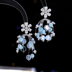 Pair of floral earrings with blue and clear gemstones on a black background