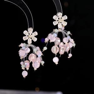 Delicate floral earrings with pink and green beads on a black background