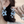 Close-up of a person wearing floral earrings with blue and clear gemstones.