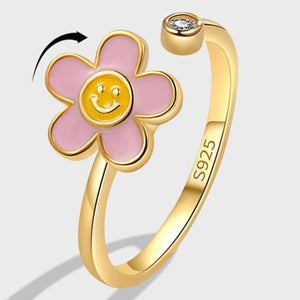 Gold flower-shaped ring with pink petals and a yellow center on a white background