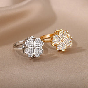 Two floral rings, one silver and one gold, on a beige fabric background