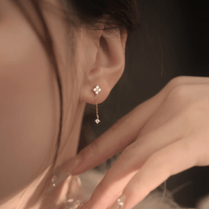 Close-up of a person wearing a delicate gold earring with a small diamond.