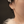 Close-up of a person wearing a silver earring with a dark background
