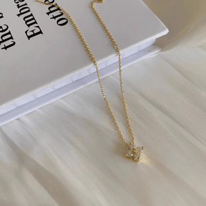 Gold necklace with a small pendant on a light surface