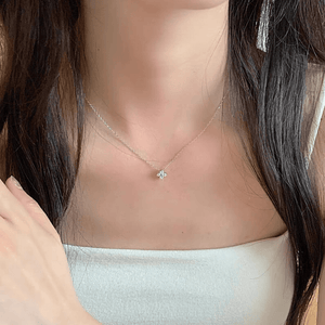 Necklace with a small pendant worn by a person with long dark hair.
