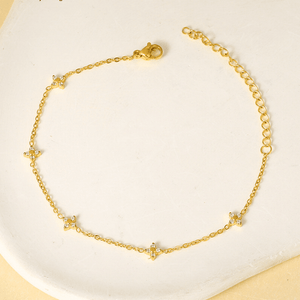 Gold anklet with star-shaped charms on a light background