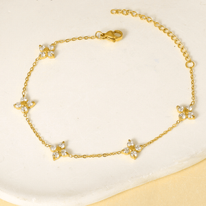 Gold bracelet with star-shaped charms on a light beige background