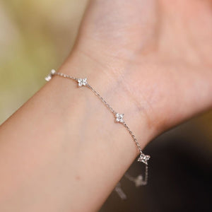 Silver anklet with floral designs on a person's ankle against a blurred background