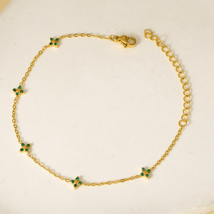 Gold bracelet with green gemstones on a light background