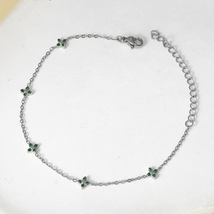 Silver bracelet with green gemstones on a white background