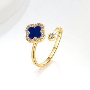 A collection of four leaf clover-shaped fidget spinner rings with various colored gemstones in silver and gold finishes.