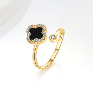 A collection of four leaf clover-shaped fidget spinner rings with various colored gemstones in silver and gold finishes.