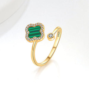 A collection of four leaf clover-shaped fidget spinner rings with various colored gemstones in silver and gold finishes.
