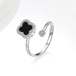 A collection of four leaf clover-shaped fidget spinner rings with various colored gemstones in silver and gold finishes.