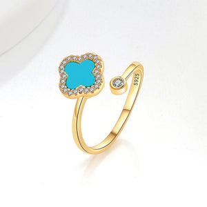 A collection of four leaf clover-shaped fidget spinner rings with various colored gemstones in silver and gold finishes.