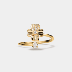 Gold ring with a bow design and small gemstones on a light gray background