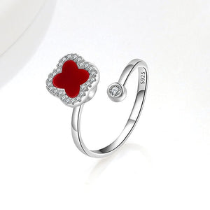 A collection of four leaf clover-shaped fidget spinner rings with various colored gemstones in silver and gold finishes.