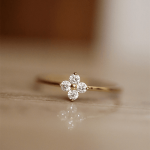 Gold ring with diamond flower design on a beige background