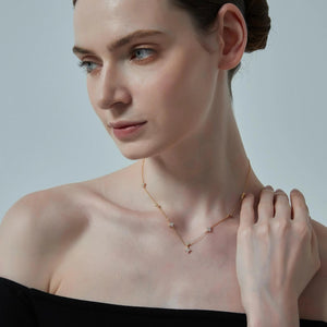 Woman wearing a delicate necklace against a neutral background