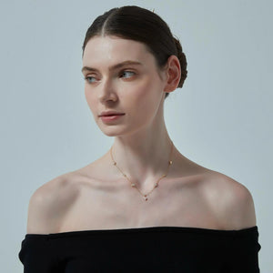 Woman wearing a delicate necklace against a plain background