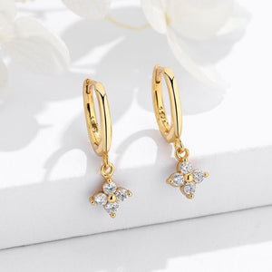 Gold hoop earrings with floral designs and diamonds on a white background