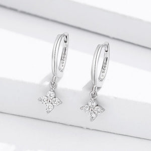 A pair of gold-plated sterling silver hoop earrings with four-petal flower drop pendants, adorned with cubic zirconia.