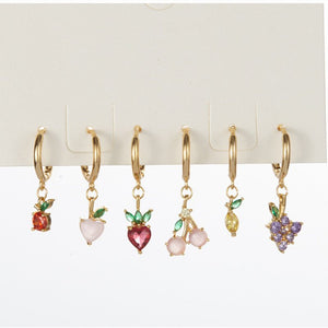 Set of gold hoop earrings with colorful fruit-shaped charms on a white background