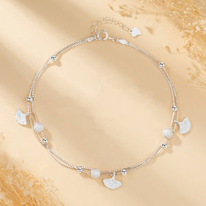 Silver bracelet with leaf-shaped charms on a beige background