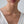 Gold necklace on a person wearing a white top against a neutral background