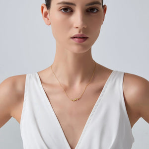 Woman wearing a gold necklace against a plain background