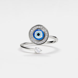 Silver spinner ring with blue evil eye design and small diamond on a light gray background