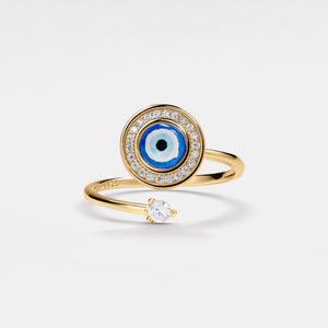 Gold spinner ring with blue evil eye design and small diamond on a light gray background