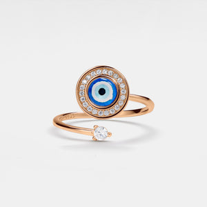 Rose gold spinner ring with blue evil eye design and small diamond on a light gray background