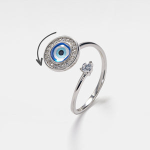 Silver spinner ring with blue evil eye design and small diamond on a light gray background
