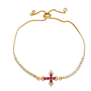 A gold-plated adjustable bracelet featuring a cross charm with cubic zirconia and small clear stones along the chain.
