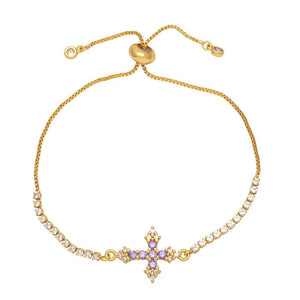 A gold-plated adjustable bracelet featuring a cross charm with cubic zirconia and small clear stones along the chain.