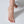 Close-up of a foot wearing a gold anklet on a light background